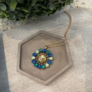 Vintage-inspired pendant features a radiant centerpiece surrounded by sparkling